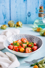 Delicious salad of tomatoes, physalis and dill in a bowl. Vegetarian food. Vertical view