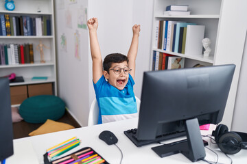 Fototapeta na wymiar Adorable hispanic boy student using laptop with cheerful expression at classroom