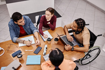 Diverse group of young people studying together in college library