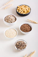 Quinoa, sesame, flax seeds, sunflower seeds and chickpeas in bowls on the table. Vertical view