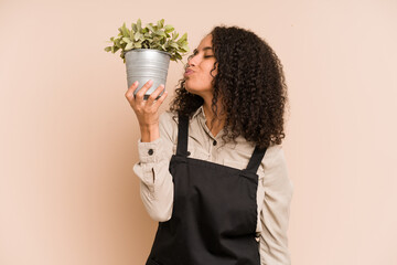 Young african american gardener woman holding a plant isolated