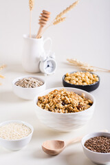 Baked granola in a bowl and different seeds in bowls on the table. Healthy breakfast. Vertical view