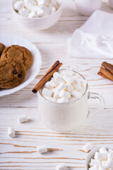 Milk latte with marshmallows in a cup and a plate with homemade cookies. Comfort food. Vertical view