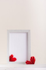 Blank photo frame decorated with DIY paper hearts. Home decor. Vertical view