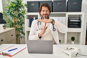 Handsome middle age doctor man working at the clinic doing time out gesture with hands, frustrated and serious face