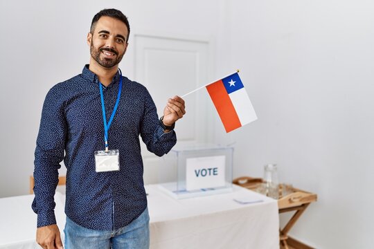 Young hispanic man smiling confident holding chile flag standing at electoral college