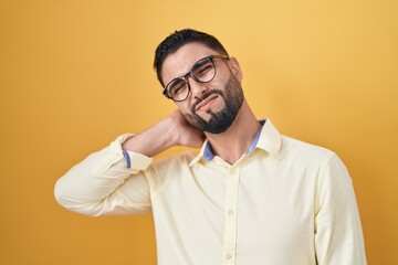 Obraz premium Hispanic young man wearing business clothes and glasses suffering of neck ache injury, touching neck with hand, muscular pain