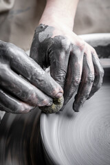 Women working at pottery wheel, creating dishes. The dirty hands of the potter in the clay and on the wheel. Creation. - 561608557