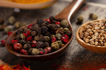 Variety of pepper spices in spoon at table background. Cooking concept and ingredients