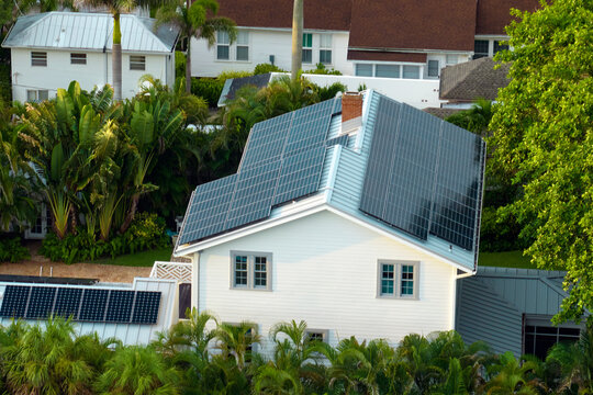 New American Residential House With Rooftop Covered With Solar Photovoltaic Panels For Producing Of Clean Electrical Energy In Suburban Rural Area. Concept Of Investment In Autonomous Home