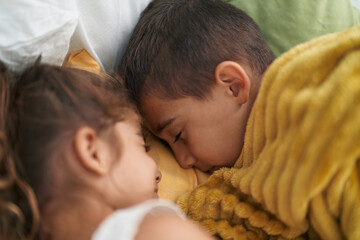 Brother and sister lying on bed sleeping at bedroom