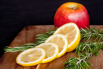 Ripe juicy apple with sliced lemon on a cutting board.
