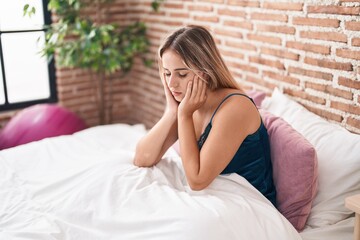 Young blonde woman stressed sitting on bed at bedroom