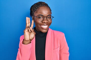 Beautiful black woman standing over blue background showing and pointing up with fingers number...