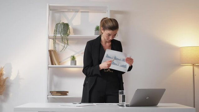 Online meeting. Angry woman. Report problem. Displeased business lady quarreling about bad work showing documents having virtual call on laptop light room interior.
