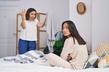 Two women mother and daughter arguing for clothes at bedroom