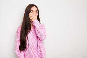Fototapeta premium Young caucasian woman isolated on white background thoughtful looking to a copy space covering mouth with hand.