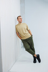 A young handsome man in casual clothes poses on a white background in the studio