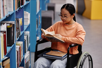 Asian girl with disability in college library reading books