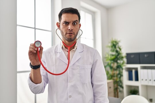 Young hispanic doctor man with beard holding stethoscope auscultating skeptic and nervous, frowning upset because of problem. negative person.