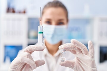 Young woman scientist holding covid vaccine at laboratory