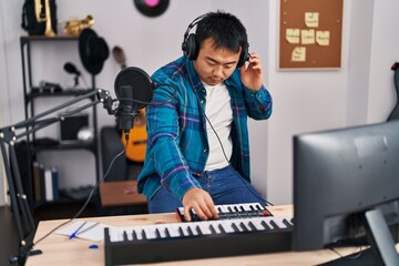 Young chinese man singer singing song playing piano keyboard at music studio