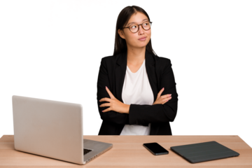 Young business asian woman sitting on a table isolated dreaming of achieving goals and purposes