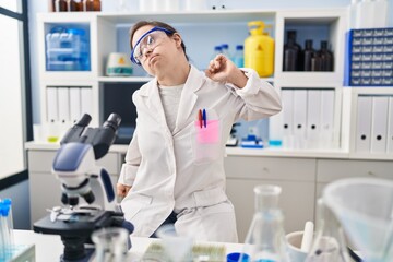 Hispanic girl with down syndrome working at scientist laboratory stretching back, tired and relaxed, sleepy and yawning for early morning