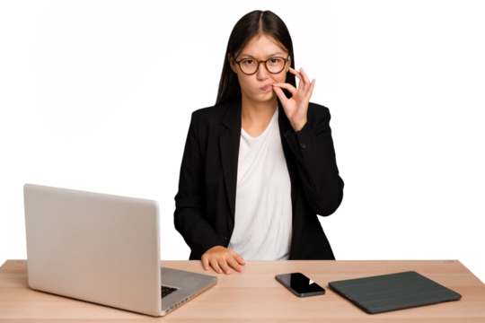 Young business asian woman sitting on a table isolated with fingers on lips keeping a secret.