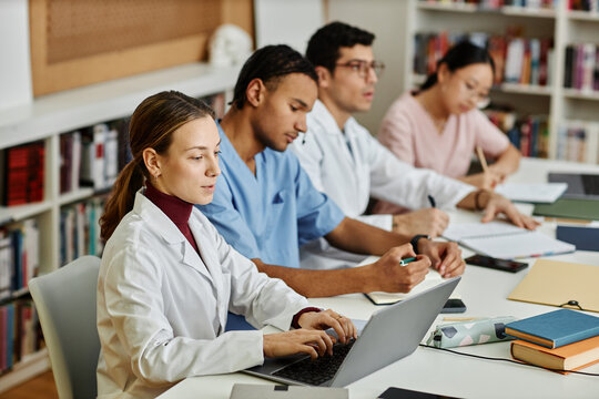 Diverse Group Of Young Med Students Sitting In Row At Table During Lecture Or Seminar