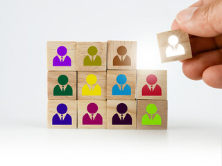 A hand placing a wooden block with colorful people icon onto many others, putting the right man into the right position, HR concept, recruitment, human resources and management