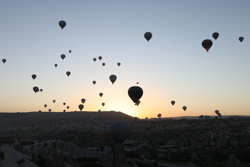 Many hot air balloons flying in sunset sky at Cappadocia, Turkey.