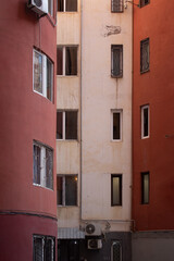 Fototapeta na wymiar Background with red and beige house wall with windows. Concept of buying an apartment in mortgage. Window pattern. Repeating row. Rhythm. Depression, loneliness. Neighbour. Real estate. District. City