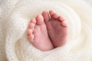 Close-up of tiny, cute, bare toes, heels and feet of a newborn girl, boy. Baby foot on white soft coverlet, blanket. Detail of a newborn baby legs.Macro horizontal professional studio photo.