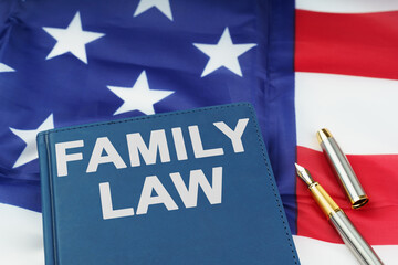 On the US flag lies a pen and a book with the inscription - FAMILY LAW