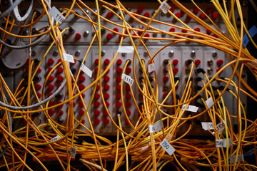 Close up background image of server cabinet with yellow internet cables and wires connected to...