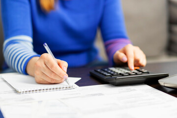 Woman using calculator for calculate domestic bills at home