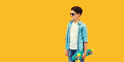 Portrait of teenager boy with skateboard looking away on colorful yellow background, blank copy space for advertising text