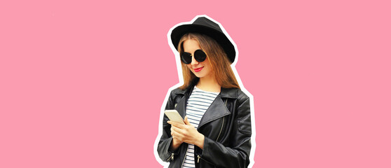 Portrait of stylish woman with smartphone wearing black round hat, leather biker rock jacket on pink background, magazine style