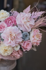 Beautiful spring flowers in box on woman hands. Preserved arrangement in grey round box. Women's day.
