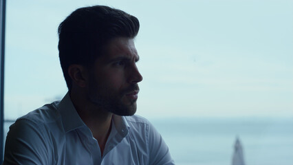 Handsome man spending leisure time in dark panoramic restaurant alone profile