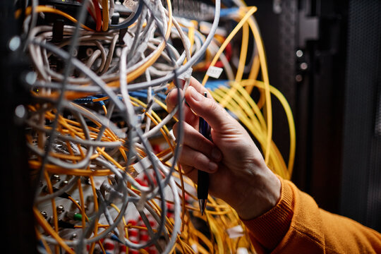 Close up of technician connecting cables and wires in server cabinet while setting up internet network, copy space