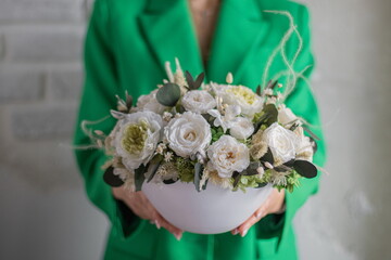 Girl in green jacket holding in her hands a of tender white flowers. Bouquet flowers a girl for...