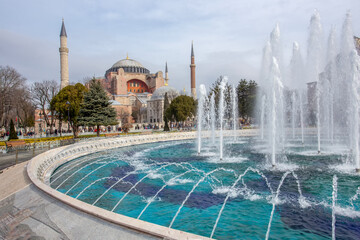 Fototapeta na wymiar Amazing landscape with shiny sun in sky and splash of water in fountain and Blue Mosque in background