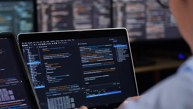Close Up Of A Tablet And Laptop'S Monitor Showing Database Being Written By A Male With Multiple Monitors Desktops. Programmer Writing Code In The Office
