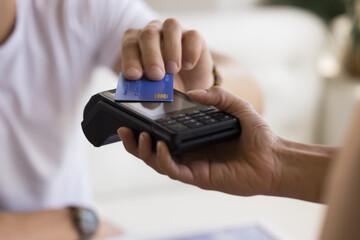 Customer man making payment for service, purchase, cashless technology, bank service, applying credit plastic card to terminal screen. Hand of shopper, buyer, seller close up cropped shot