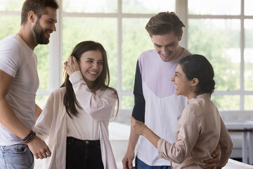 Diverse group of friends standing in cafe interior, chatting, talking, laughing, having fun. Multiethnic couples enjoying leisure, communication, double date, hugging