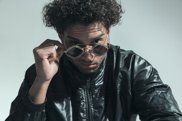 handsome arabic man with curly hair looking over sunglasses