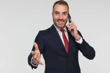 Naklejka premium happy elegant man having a phone call and making a hand gesture