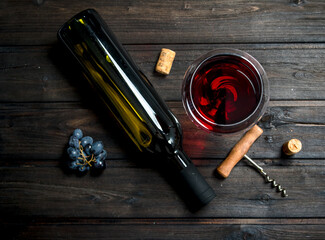 glass of red wine with a corkscrew and corks.